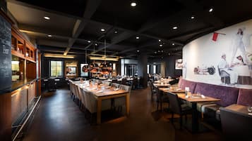 Ein Restaurantinneres mit langen Gemeinschaftstischen, einzelnen Sitzecken und einem Barbereich.