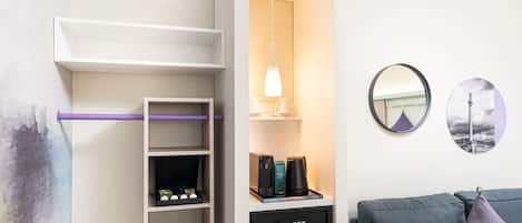 A modern room with a built-in wardrobe, a coffee machine, and a wall-mounted mirror.