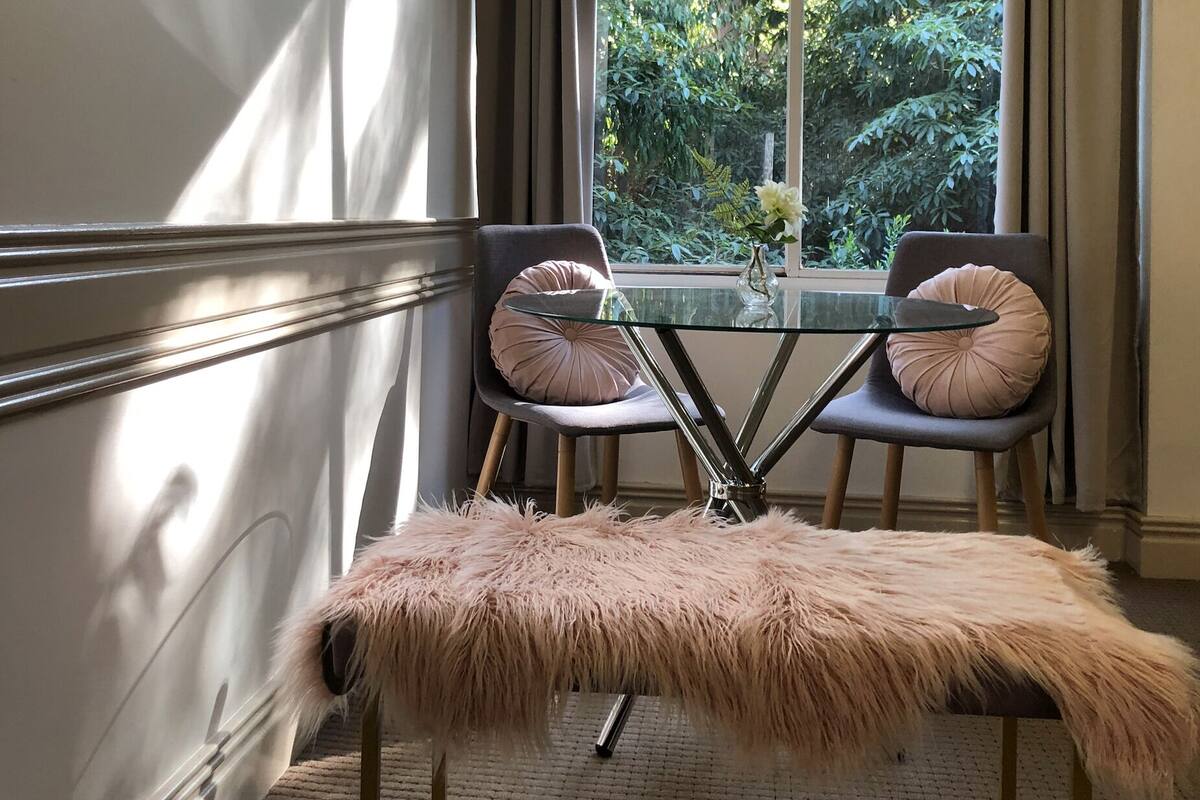 Un comedor con una mesa de vidrio y dos sillas, cada una con un cojín mullido.
