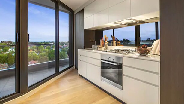 Una cocina moderna con un ventanal grande, vistas a zonas verdes y un horno empotrado.