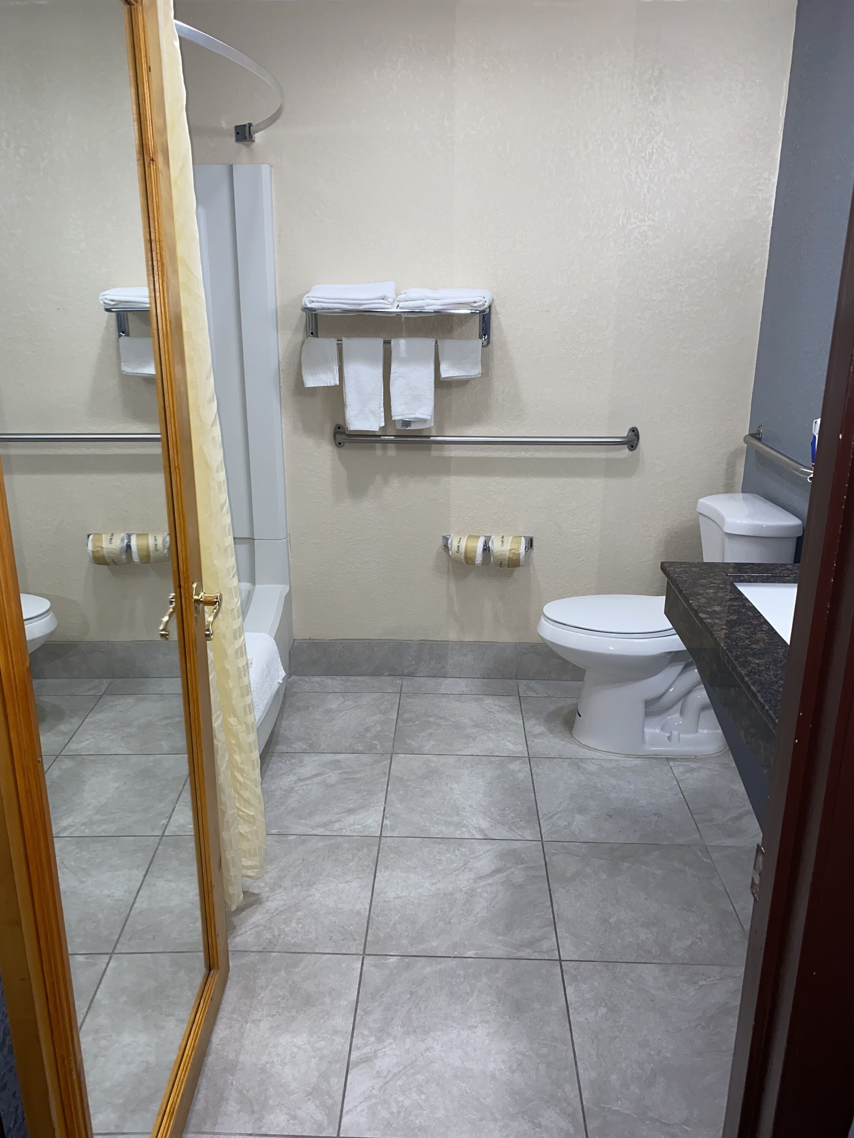 Un baño con dos inodoros, un lavamanos, una ducha y un perchero para toallas.