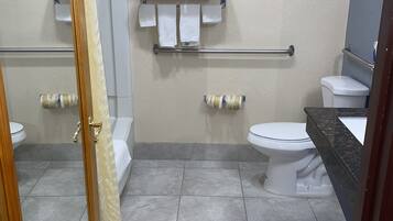 Un baño con dos inodoros, un lavamanos, una ducha y un perchero para toallas.