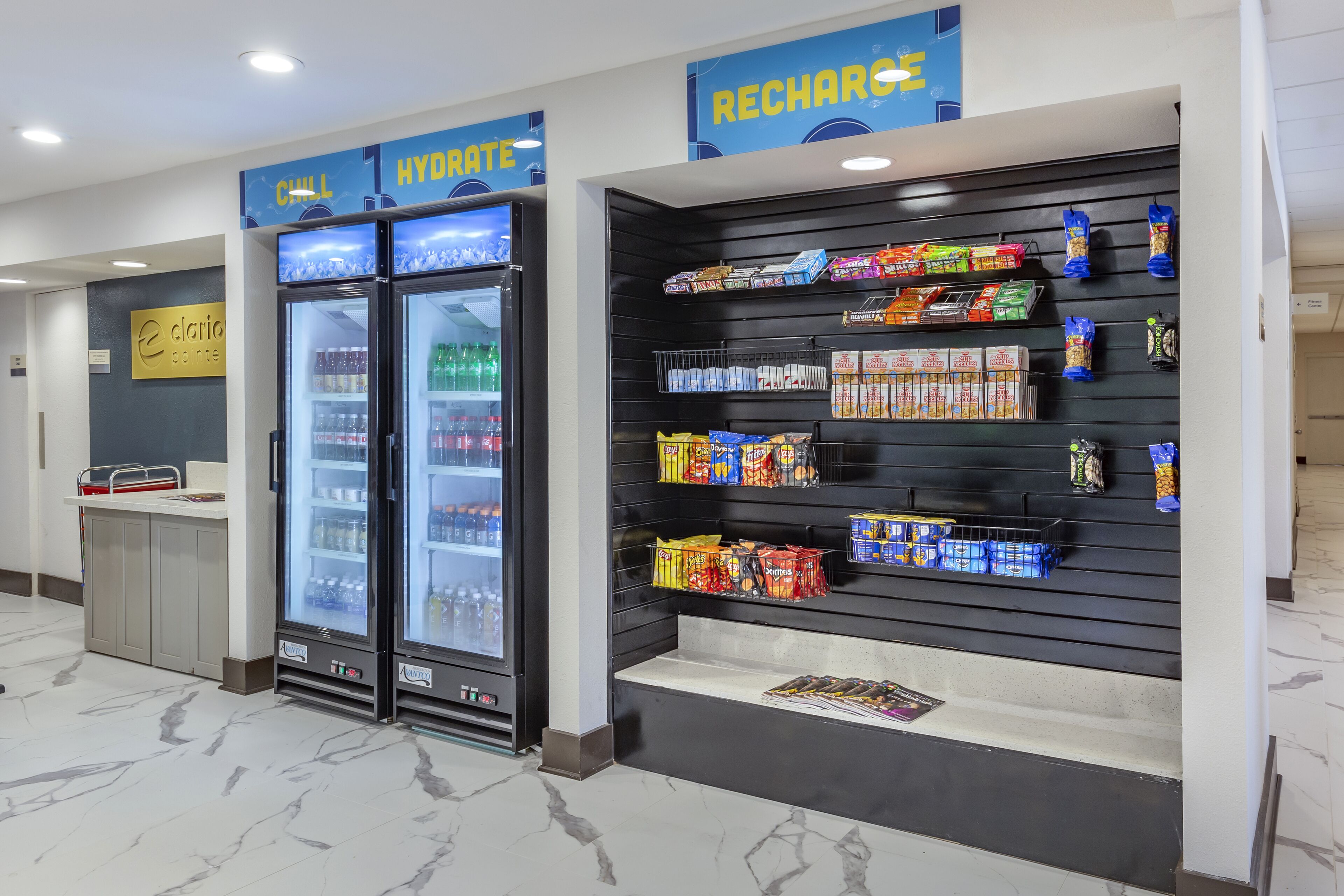 A hotel lobby with a minibar area, including a refrigerator and a snack display.