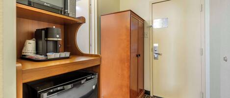 A compact hotel room with a kitchenette, including a microwave, coffee maker, and dishwasher.