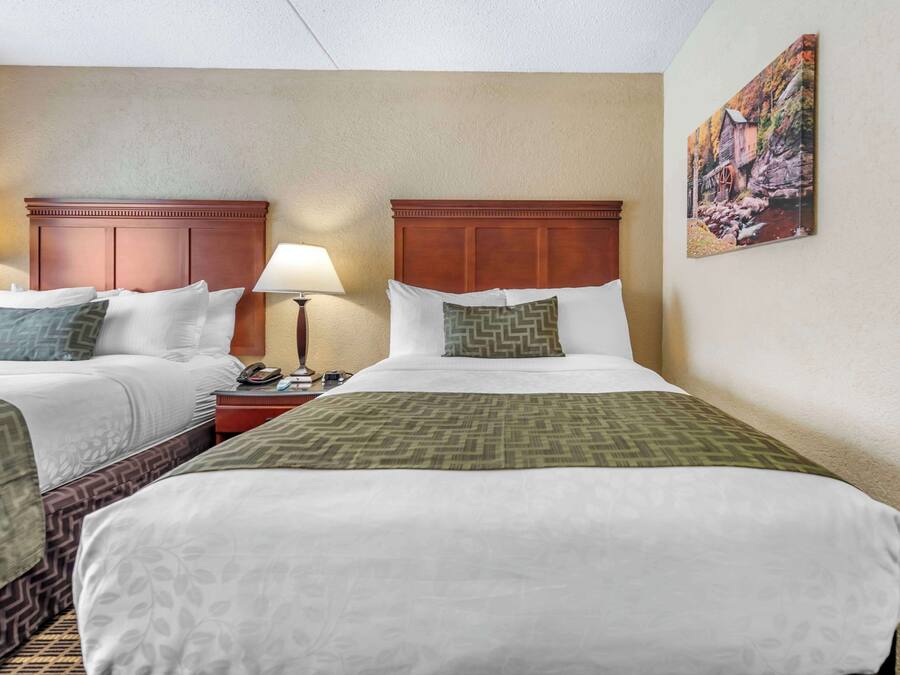 Une chambre d’hôtel avec deux lits, une table de chevet, une lampe et un tableau au mur.