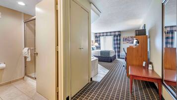 A hotel room with a bathroom, a bed, a small table, and a mirror.