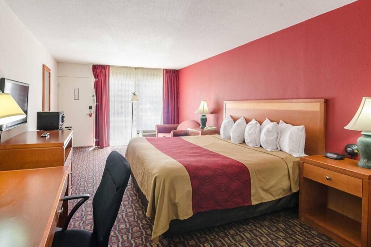 A hotel room with a bed, desk, chair, and a television.