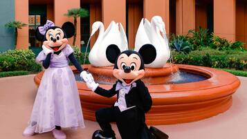 Mickey and Minnie Mouse posing in front of a fountain with swans.