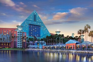 A large hotel with a distinctive pyramid-shaped building, a waterfront, and palm trees.