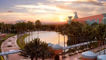 A resort with a large pool, palm trees, and a sunset view.