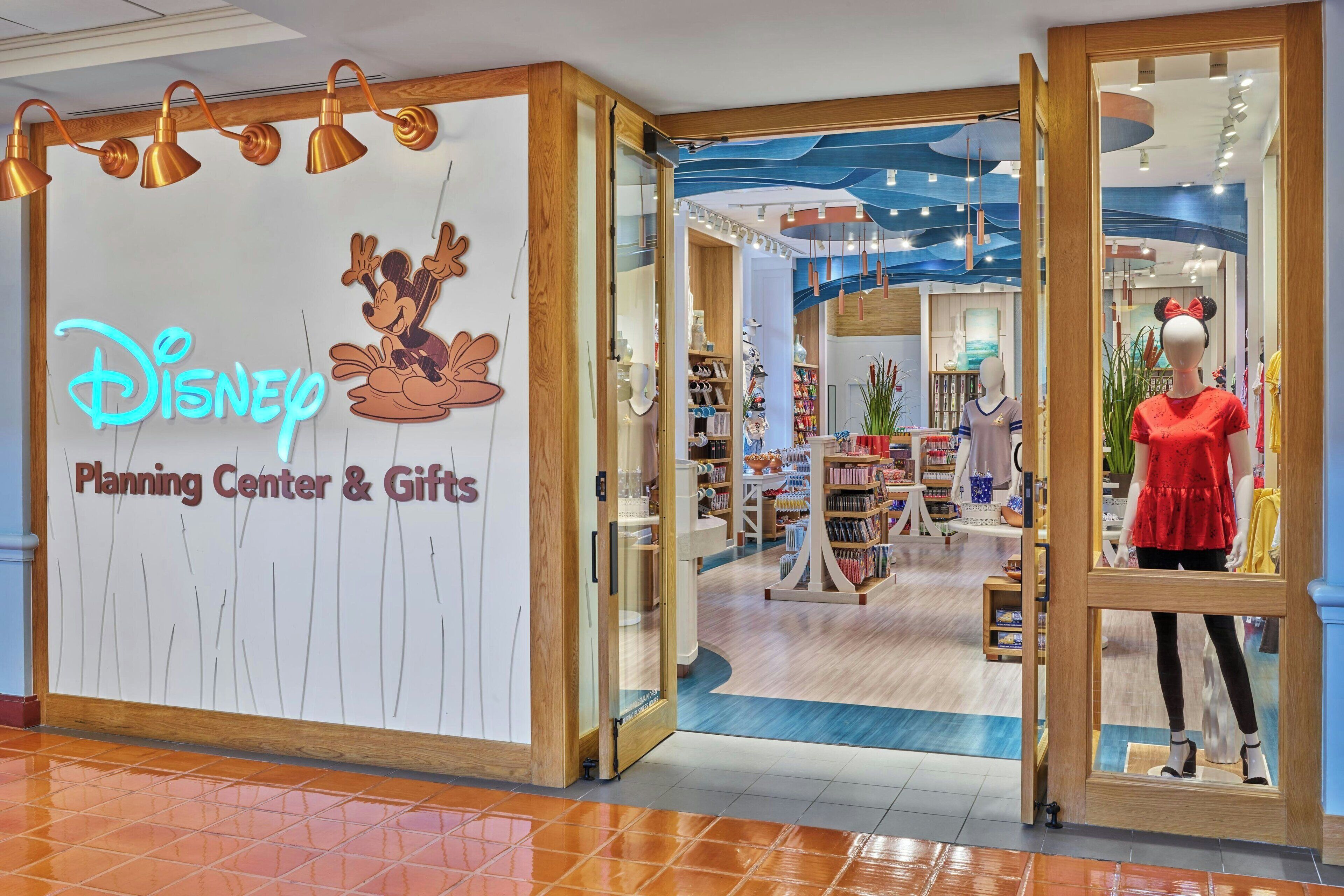 A Disney Planning Center & Gifts store with a Mickey Mouse logo, mannequins, and a variety of merchandise.