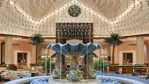A luxurious lobby with a central fountain, seating areas, and a decorative ceiling.