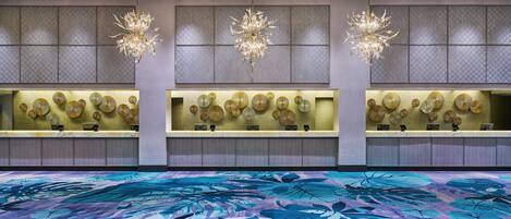 A reception area with a patterned carpet, a wall of decorative items, and three chandeliers.