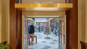 A Disney Gifts & Sundries store with a hexagonal tiled floor, wooden display cases, and shelves stocked with merchandise.