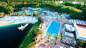 An aerial view of a resort with multiple swimming pools, a beach area, and a variety of outdoor seating arrangements.