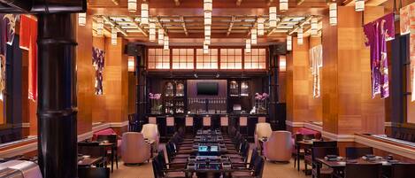 A spacious bar area with multiple seating arrangements, a central bar counter, and a television screen.
