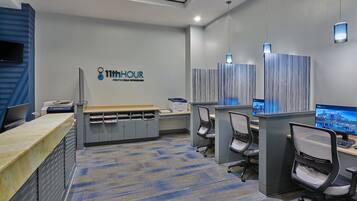Un ufficio moderno con scrivania accoglienza, diverse postazioni di lavoro e un grande monitor che mostra una vista sulla città.