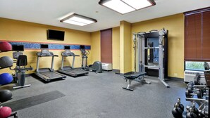Un gimnasio con cintas de correr, elípticas, una jaula para sentadillas y pesas sueltas.