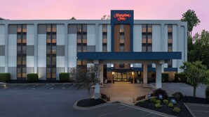 Un hotel Hampton Inn con fachada moderna, grandes ventanales y una entrada bien iluminada.