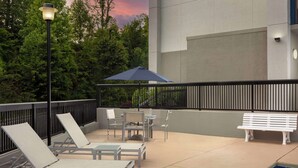 Zona de piscina al aire libre con sillas de descanso, una mesa y un banco.