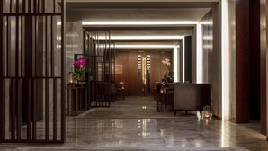 Un moderno vestíbulo de hotel con suelo de mármol, mostrador de recepción de madera y un espejo grande.