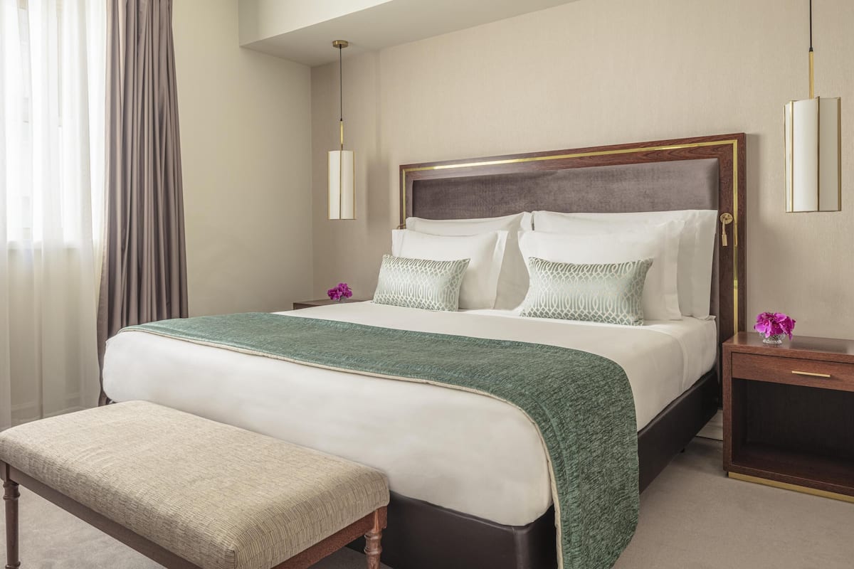 Ein Hotelzimmer mit einem großen Bett, einer Bank, einem Nachttisch und einer Wandlampe.