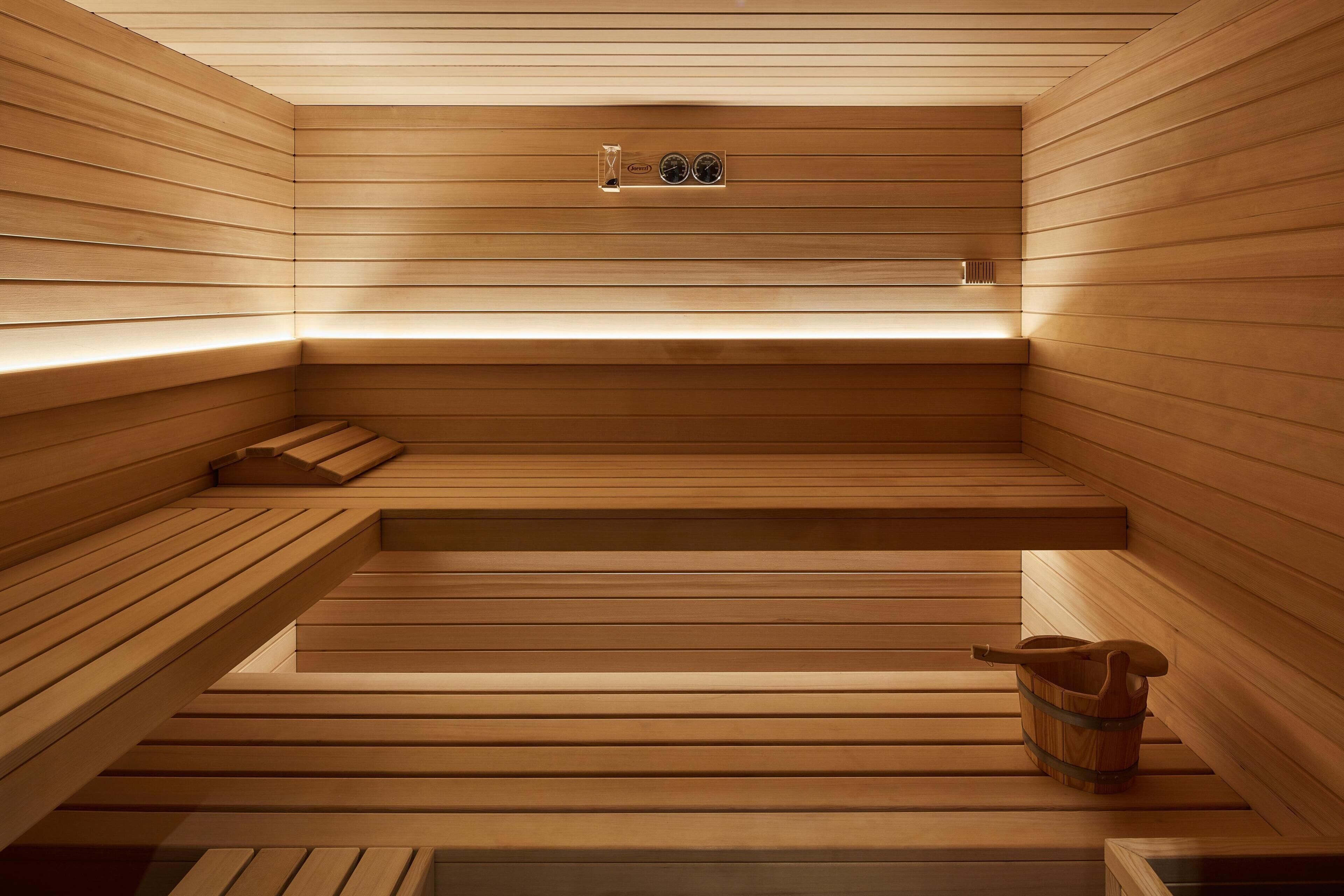 A sauna with wooden benches and a bucket.