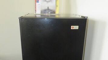 Un refrigerador negro con un adhesivo en la puerta, sobre una alfombra estampada.