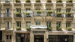 Un hotel de varios pisos con balcones decorados con jardineras, una entrada destacada y señalización para un bar y una sala de reuniones.