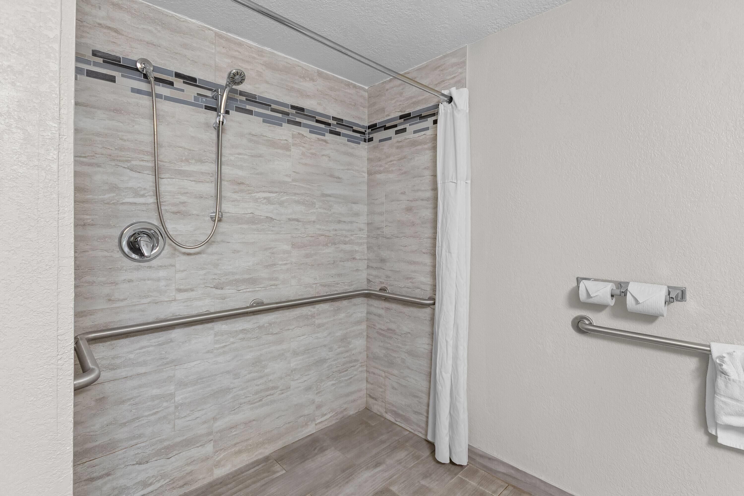 Un espace douche équipé d’une barre d’appui, d’une porte en verre et d’un porte-serviettes.