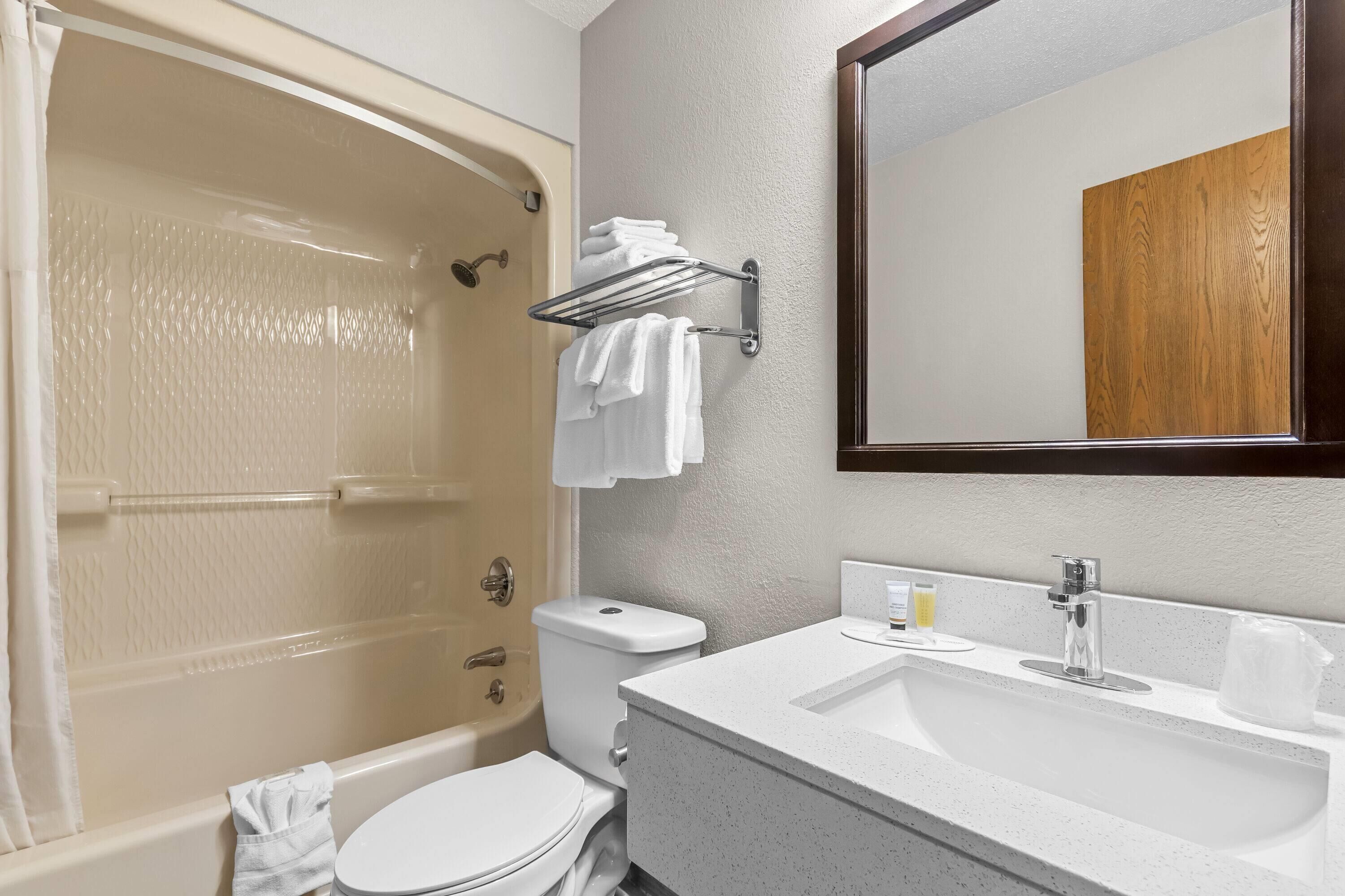 Een badkamer met een bad, toilet, wastafel en een handdoekrek.