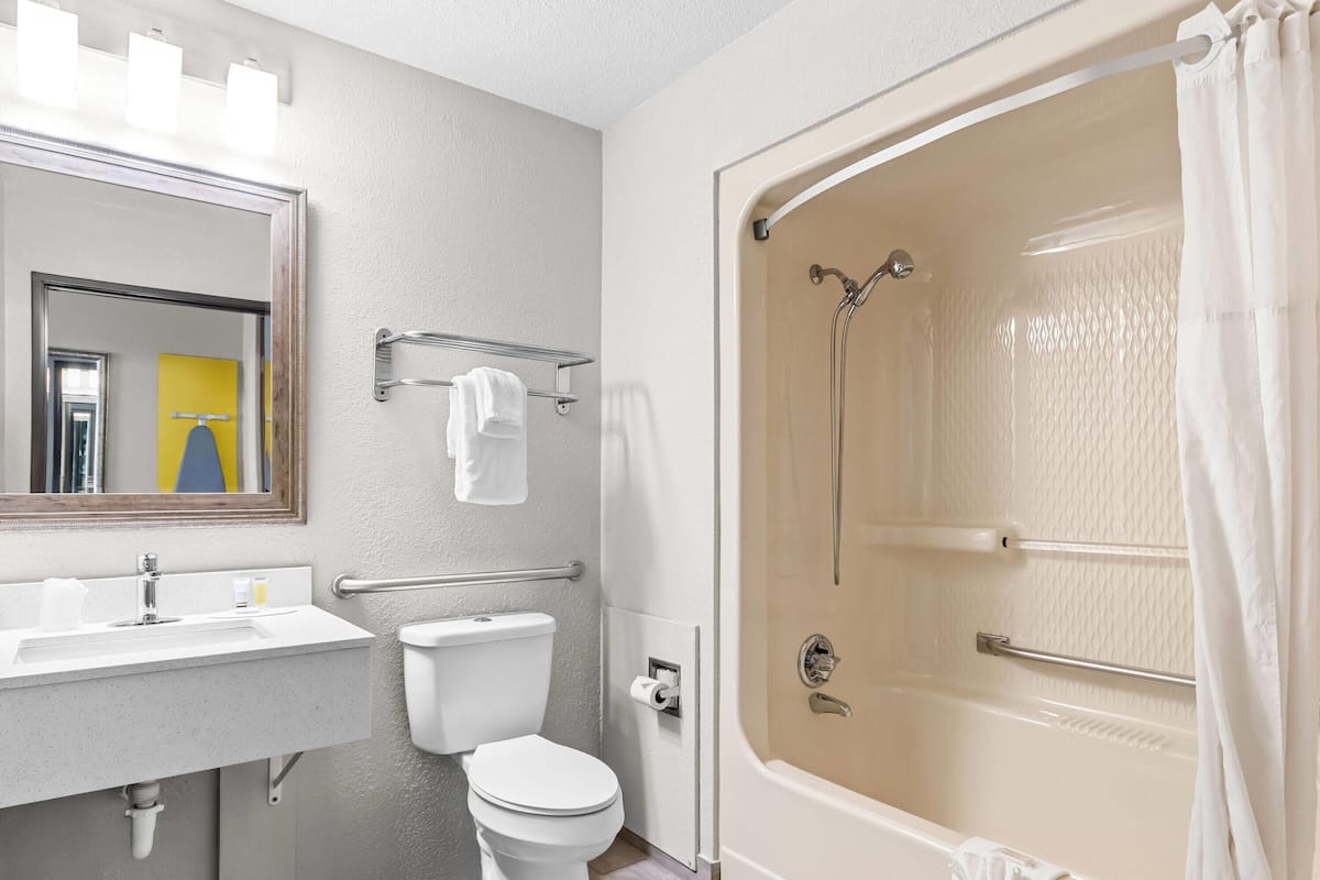 A bathroom with a toilet, sink, mirror, and shower.