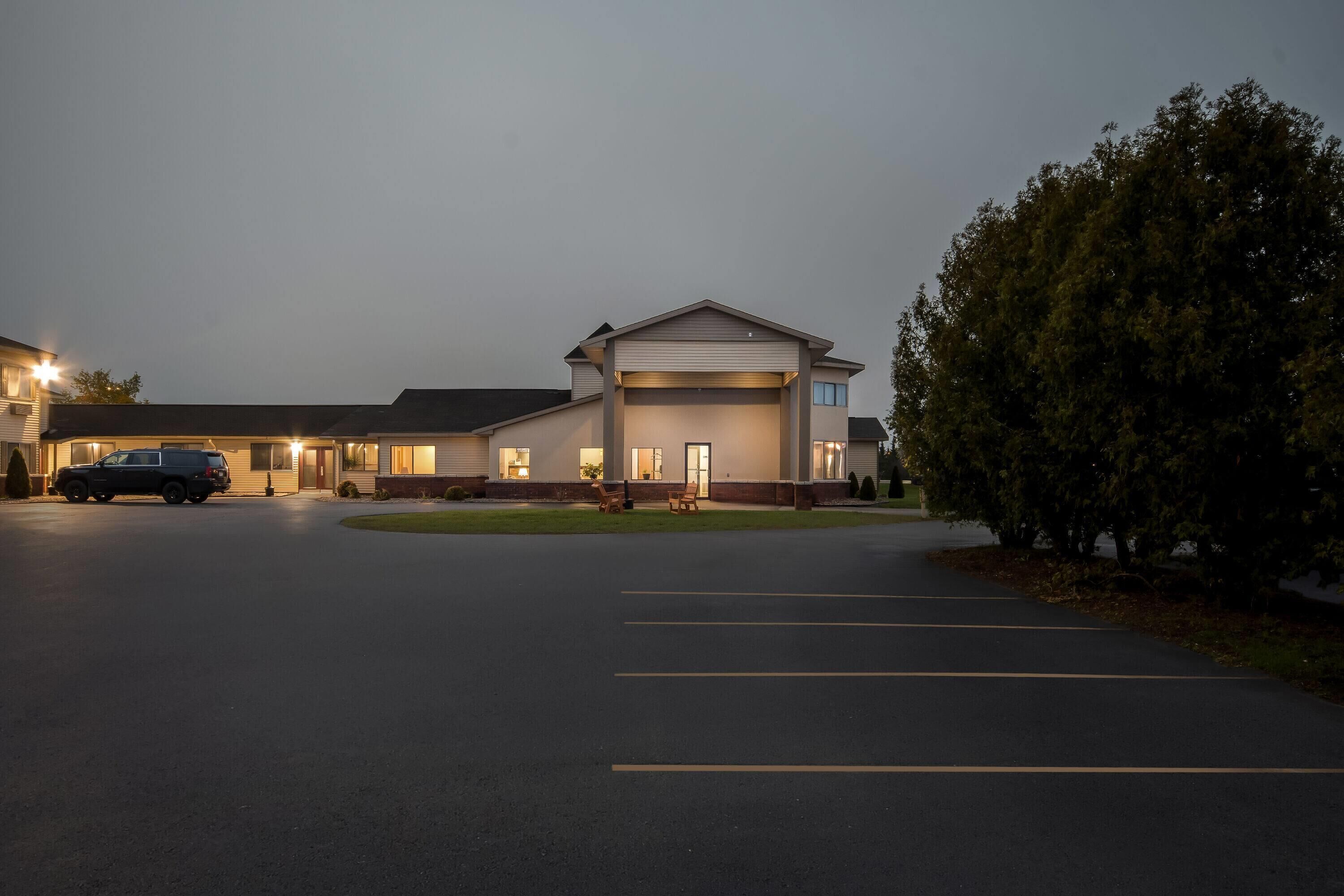 A building with a garage, a parking lot, and a tree.