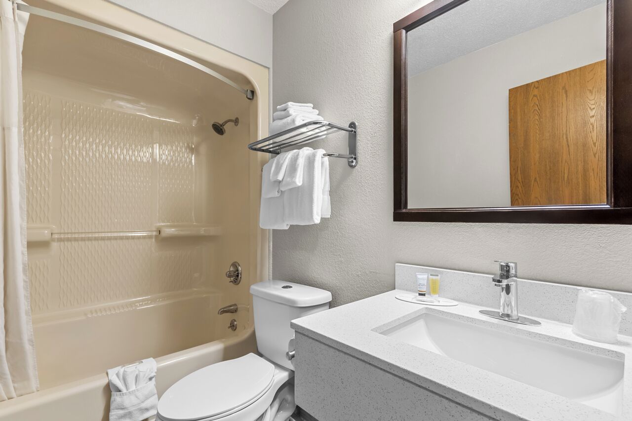 A bathroom with a bathtub, toilet, sink, and a mirror.