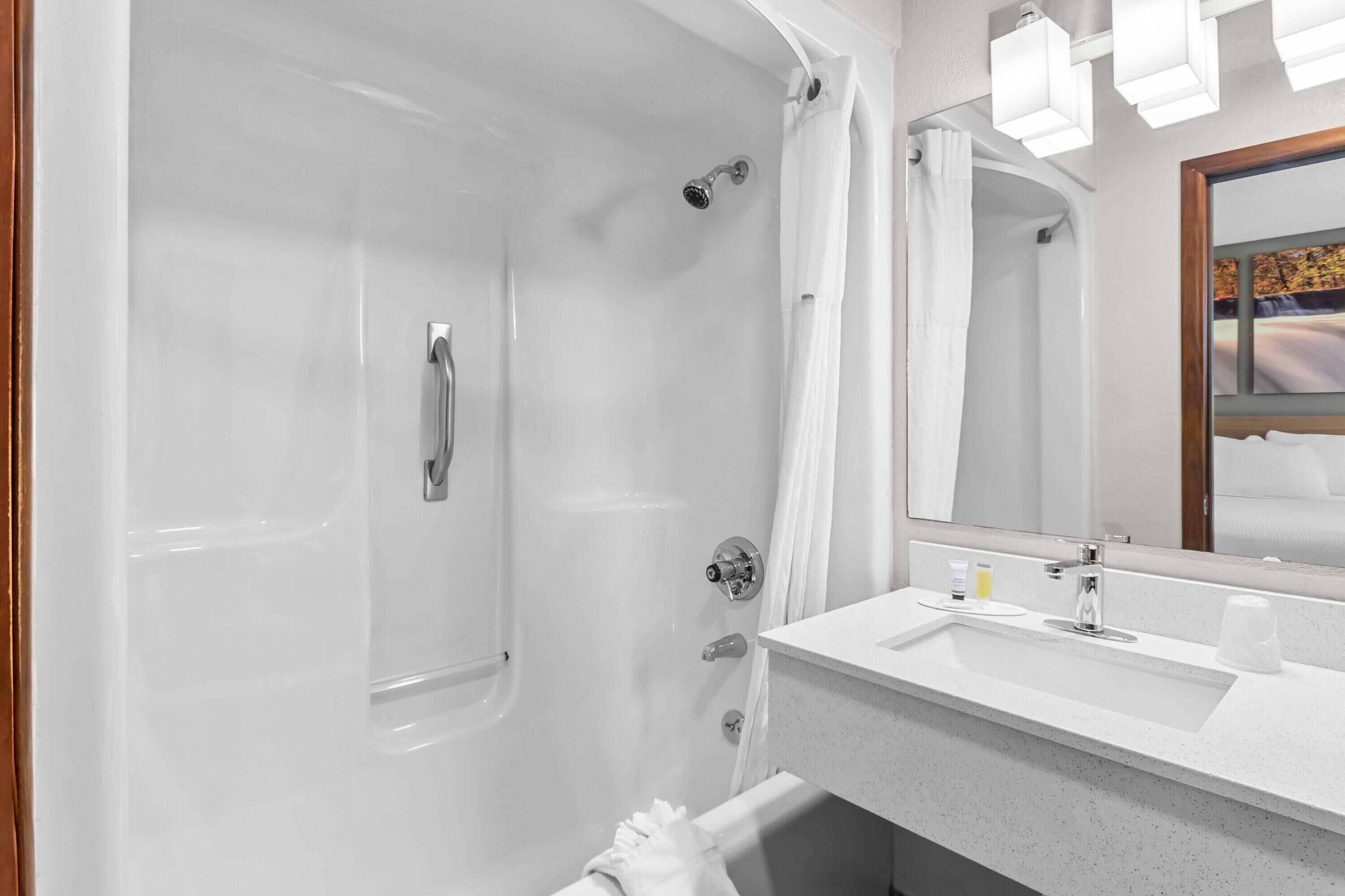 A modern bathroom with a bathtub, a sink, and a mirror.