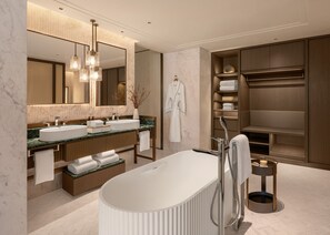 Ein modernes Badezimmer mit einer freistehenden Badewanne, zwei Waschbecken, einem großen Spiegel und einem begehbaren Kleiderschrank mit Regalen.