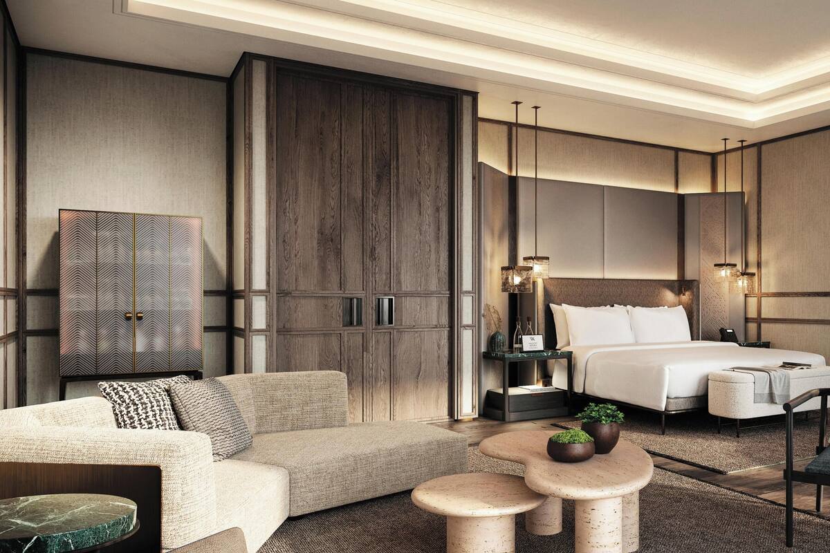Een moderne hotelkamer met een groot bed, een bank, een klein tafeltje en een stoel.