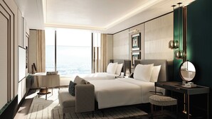 Ein Hotelzimmer mit einem großen Bett, einem Schreibtisch, einem Stuhl, einem Spiegel und Blick auf die Stadt.