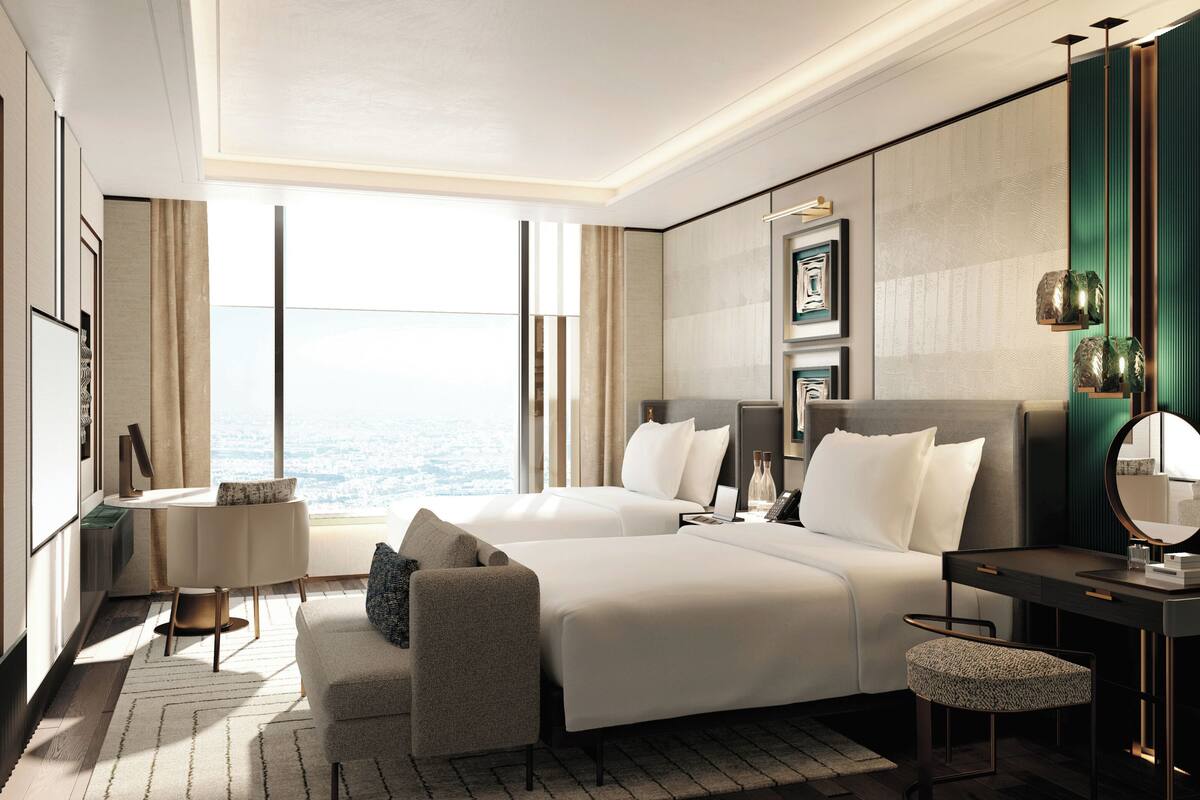 Hotelkamer met een groot bed, een bureau, een stoel, een spiegel en uitzicht op de stad.