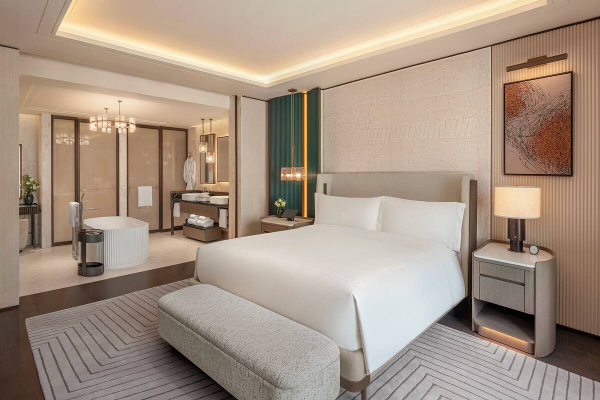 Een moderne hotelkamer met een groot bed, een zithoek, een kaptafel met spiegel en een badkamer.