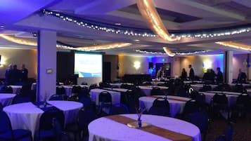 A conference room with round tables, chairs, and a presentation screen.
