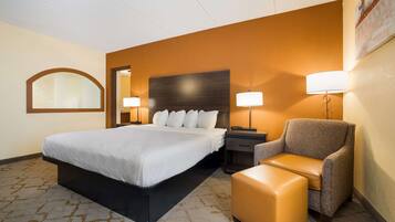 Una habitación de hotel con una cama grande, una silla, una mesita de noche y una lámpara.