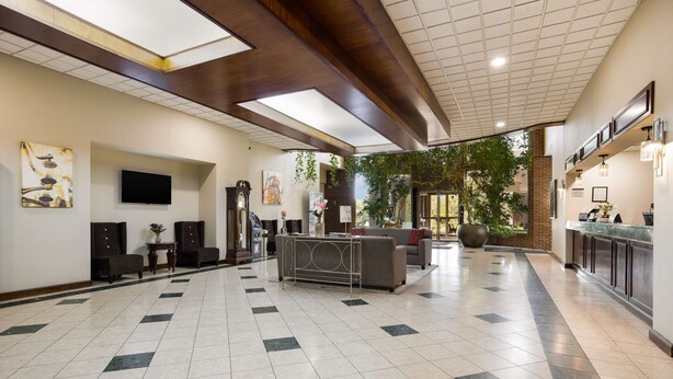 Um hall amplo com piso xadrez, um sofá, uma mesa de centro, uma televisão e um balcão de recepção.