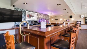 Uma área de bar com balcão de madeira, banquetas e um quadro de cardápio.