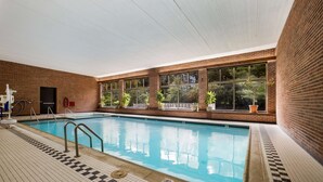Piscina interior com chão ladrilhado e parede de tijolos.