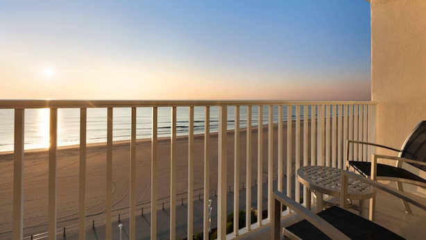 A balcony with a view of the beach and ocean during sunset. - Surfbreak Virginia Beach Oceanfront, an Ascend Collection Hotel (Virginia Beach)