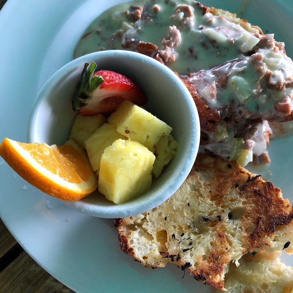 A plate with a bowl of fruit, a slice of toast, and a creamy dish.