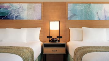 Habitación de hotel con dos camas, una mesita de noche con un reloj y arte abstracto en la pared.