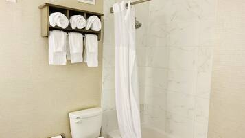 A bathroom with a toilet, a shower with a glass door, and a towel rack with multiple towels.