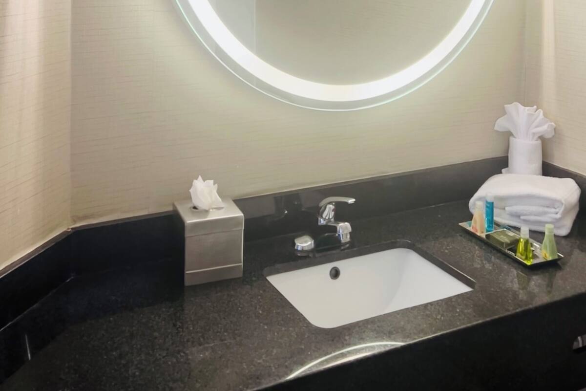 A bathroom with a round mirror, a sink, and a towel rack.